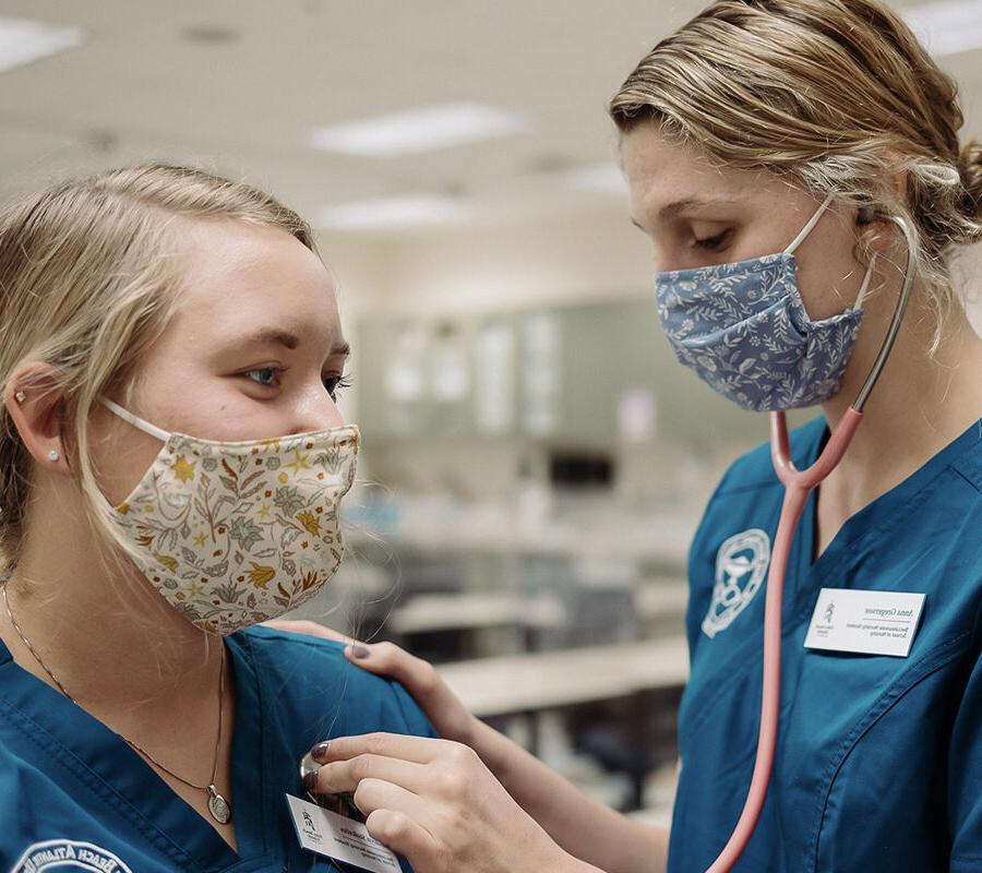 一个护理专业的学生通过听诊器听另一个学生的心跳